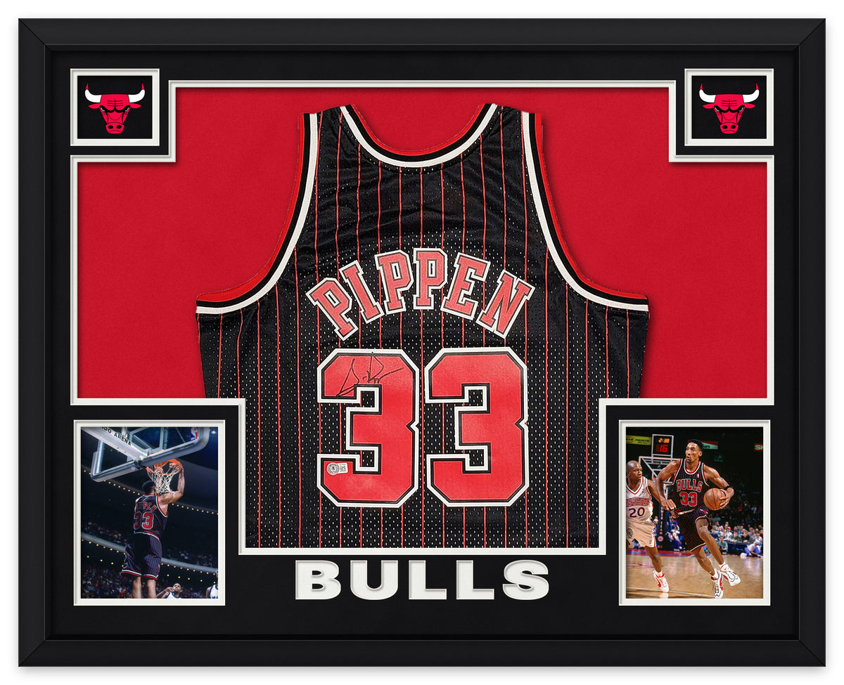 Scottie Pippen signed black pinstripe Chicago Bulls number 33 jersey in a black frame with black matting, red backing, Bulls logos, two photos of Pippen and BULLS lettering