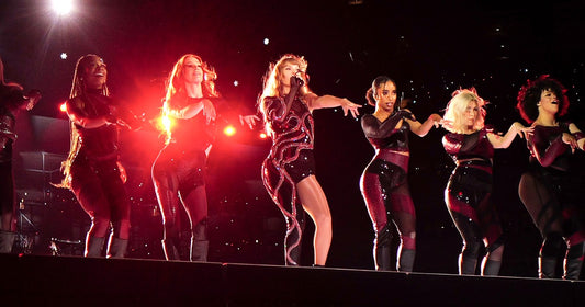 Taylor Swift performing with her dancers during the Reputation act of the Eras Tour, lit in red on a darkened stadium stage