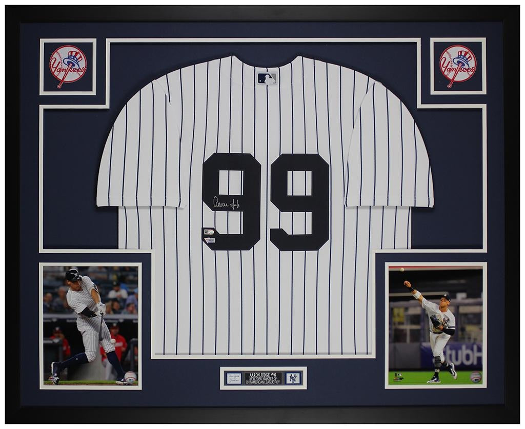 Aaron Judge signed New York Yankees #99 pinstriped home jersey in a custom frame with navy mat, two Yankees logo patches, two action photos and an engraved nameplate