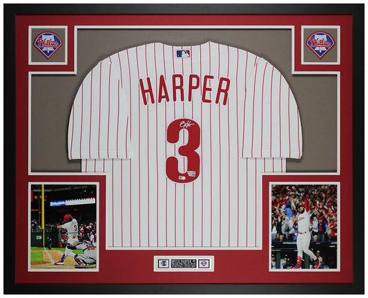 Bryce Harper signed Philadelphia Phillies #3 pinstriped home jersey in a custom frame with red and gray mat, two Phillies logo patches, two action photos and an engraved nameplate