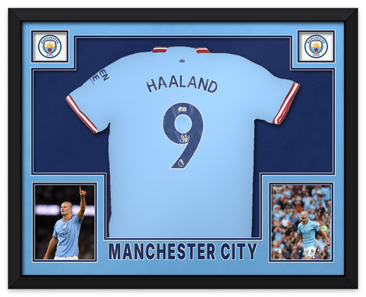 Erling Haaland signed sky blue Manchester City number 9 home shirt, signed in silver ink with the Beckett Witnessed hologram, shown in a black custom frame with sky blue and navy matting, Manchester City crests in the upper corners, two photographs and MANCHESTER CITY lettering