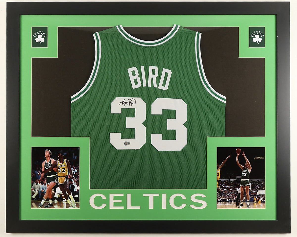 Larry Bird signed green Boston Celtics number 33 jersey in black marker with the Beckett hologram, in a black custom frame with light green matting, Celtics shamrocks in the upper corners, two photographs and CELTICS lettering