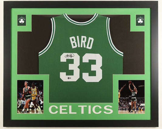 Larry Bird signed green Boston Celtics number 33 jersey in black marker with the Beckett hologram, in a black custom frame with light green matting, Celtics shamrocks in the upper corners, two photographs and CELTICS lettering