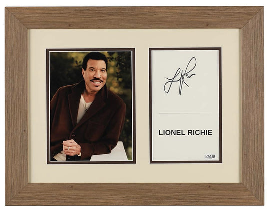 Lionel Richie signed framed display: a color portrait of Richie in a brown jacket beside a name card hand-signed in black ink, in a cream mat with dark brown borders and a wood-grain frame, JSA authenticated