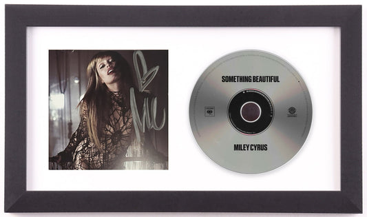 Miley Cyrus signed Something Beautiful framed CD display: signed photo insert of Cyrus in black lace, beside the silver album disc, in a white mat and black frame