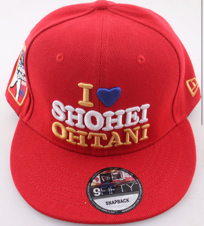 Front of the red I Love Shohei Ohtani New Era 9FIFTY snapback with a gold I, royal blue heart, white SHOHEI and gold OHTANI