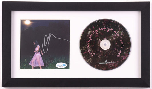 Olivia Rodrigo signed you seem pretty sad for a girl so in love framed CD display: night photo of Rodrigo in a sheer pink dress in tall grass under a full moon, signed in silver marker, ACOA label on the lower right, beside the floral album disc in a white mat and black frame