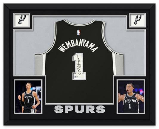 Victor Wembanyama signed black San Antonio Spurs number 1 jersey, signed in black ink with the Beckett hologram, shown in a black custom frame with black and silver matting, Spurs logos in the upper corners, two photographs and SPURS lettering